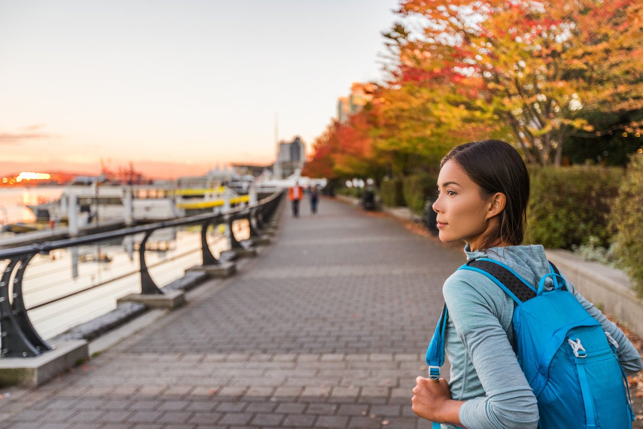 Vancouver city urban lifestyle people at Harbour, British Columbia. Woman tourist with student backpack in city outdoors enjoying autumn season.