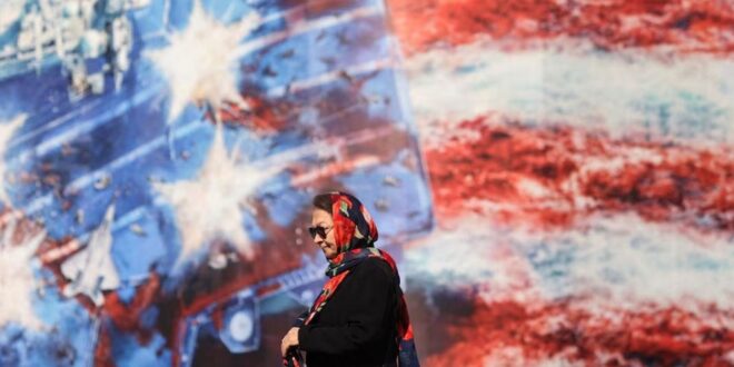 An Iranian woman walks past an anti-US billboard in Tehran, Iran on February 26, 2026. M