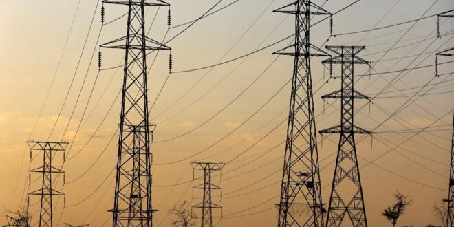 FILE: A man walks beneath electricity pylons.
