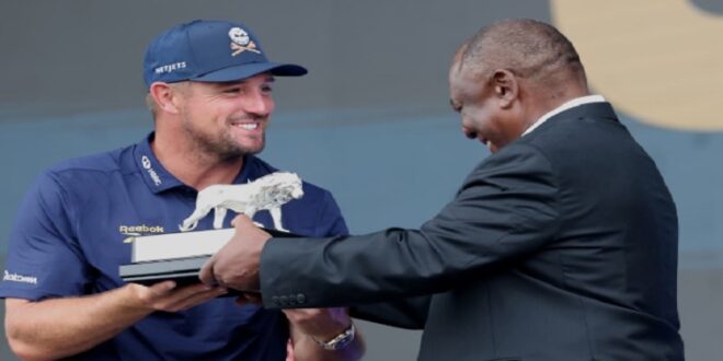 LIV Golf SA title winner Bryson DeChambeau holds the trophy together with President Cyril Ramaphosa.