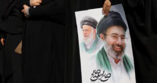 A woman holds an image of Iran's new supreme leader, Mojtaba Khamenei, alongside late Iranian Supreme Leader Ayatollah Ali Khamenei, during a funeral ceremony for the Iranian military commanders who were killed in strikes, amid the U.S.-Israeli conflict with Iran, in Tehran, Iran, March 11, 2026.