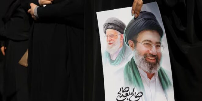 A woman holds an image of Iran's new supreme leader, Mojtaba Khamenei, alongside late Iranian Supreme Leader Ayatollah Ali Khamenei, during a funeral ceremony for the Iranian military commanders who were killed in strikes, amid the U.S.-Israeli conflict with Iran, in Tehran, Iran, March 11, 2026.