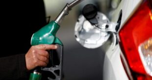 A man holds a fuel nozzle at a petrol station.