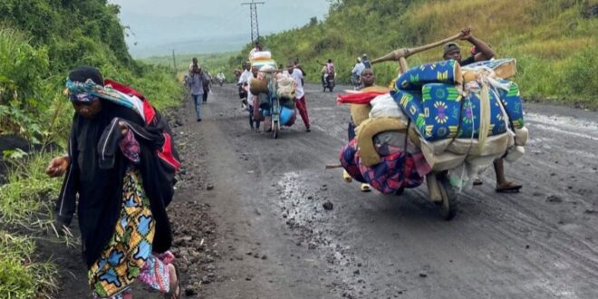 Civilians push their belongings on a wooden handcart known as Tshikudu as they flee after heavy gunfire that raised fears of M23 rebels advancing along a road from Sake near Goma in the North Kivu province of the Democratic Republic of Congo on February 9, 2023.